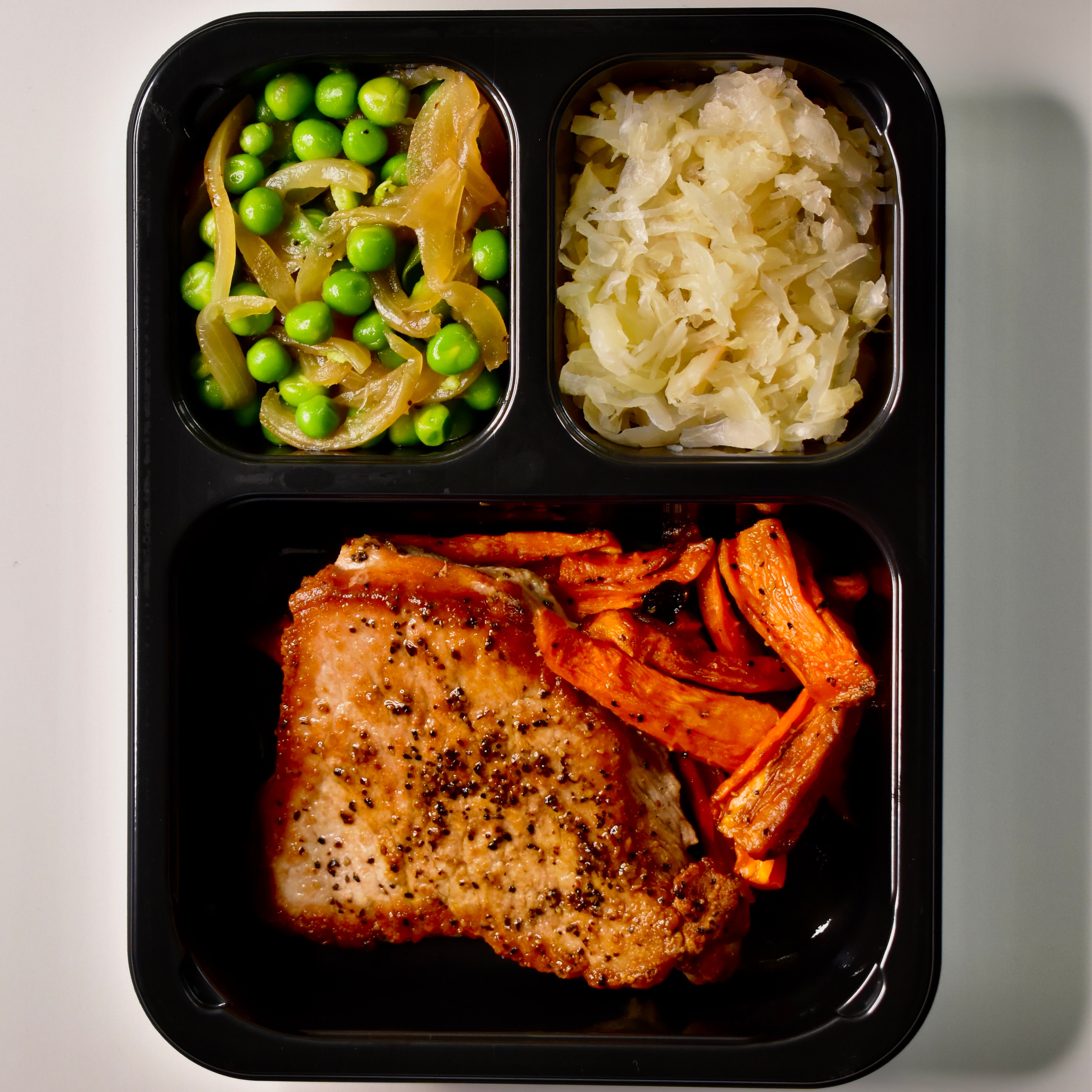 Roasted Pork Loin with Sauerkraut, Sautéed Onions & Green Peas, and Roasted Carrots